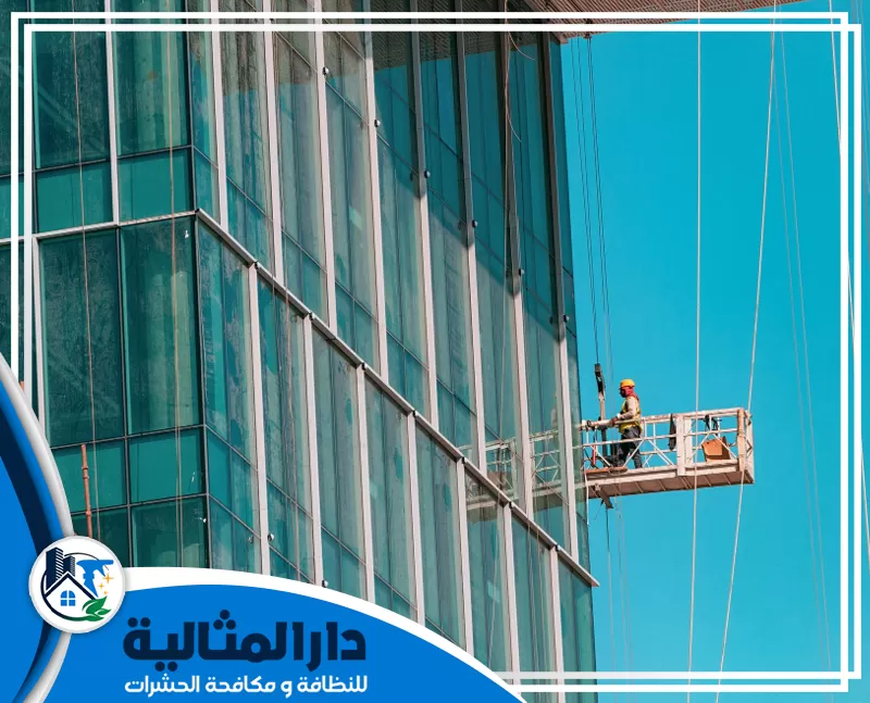 أفضل شركة تنظيف واجهات زجاج بالخبر | 0598198483 | دار المثالية عامل يقف علي رافعه يعمل علي تنظيف واجهات زجاج المباني بالخبر باستخدام أحدث المعدات.