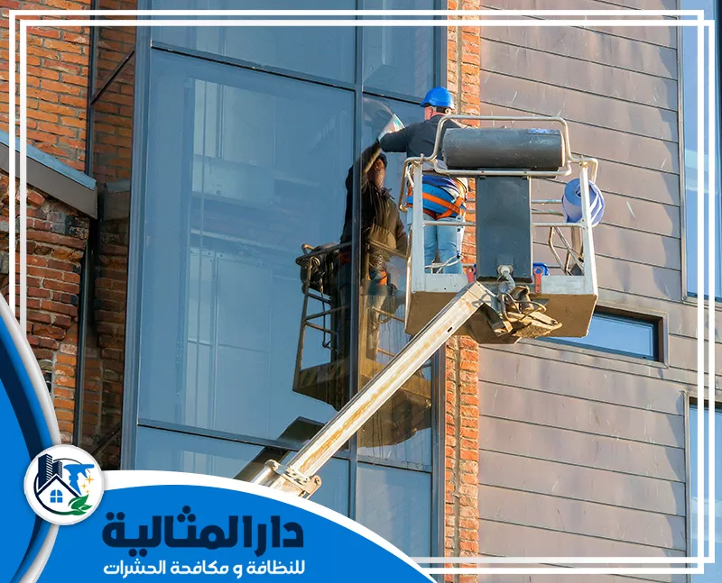 افضل شركة تنظيف واجهات زجاج بالقطيف | 0598198483 | دار المثالية عامل على رافعة يقوم بأعمال تنظيف واجهات زجاج لمبنى في القطيف.