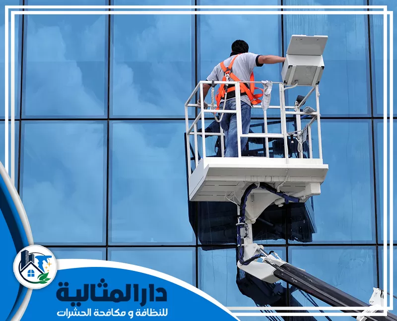 افضل شركات تنظيف واجهات زجاج بالقطيف | 0598198483 | دار المثالية رجل على مصعد يقوم بتنظيف الواجهة الزجاجية لمبنى حديث في القطيف.